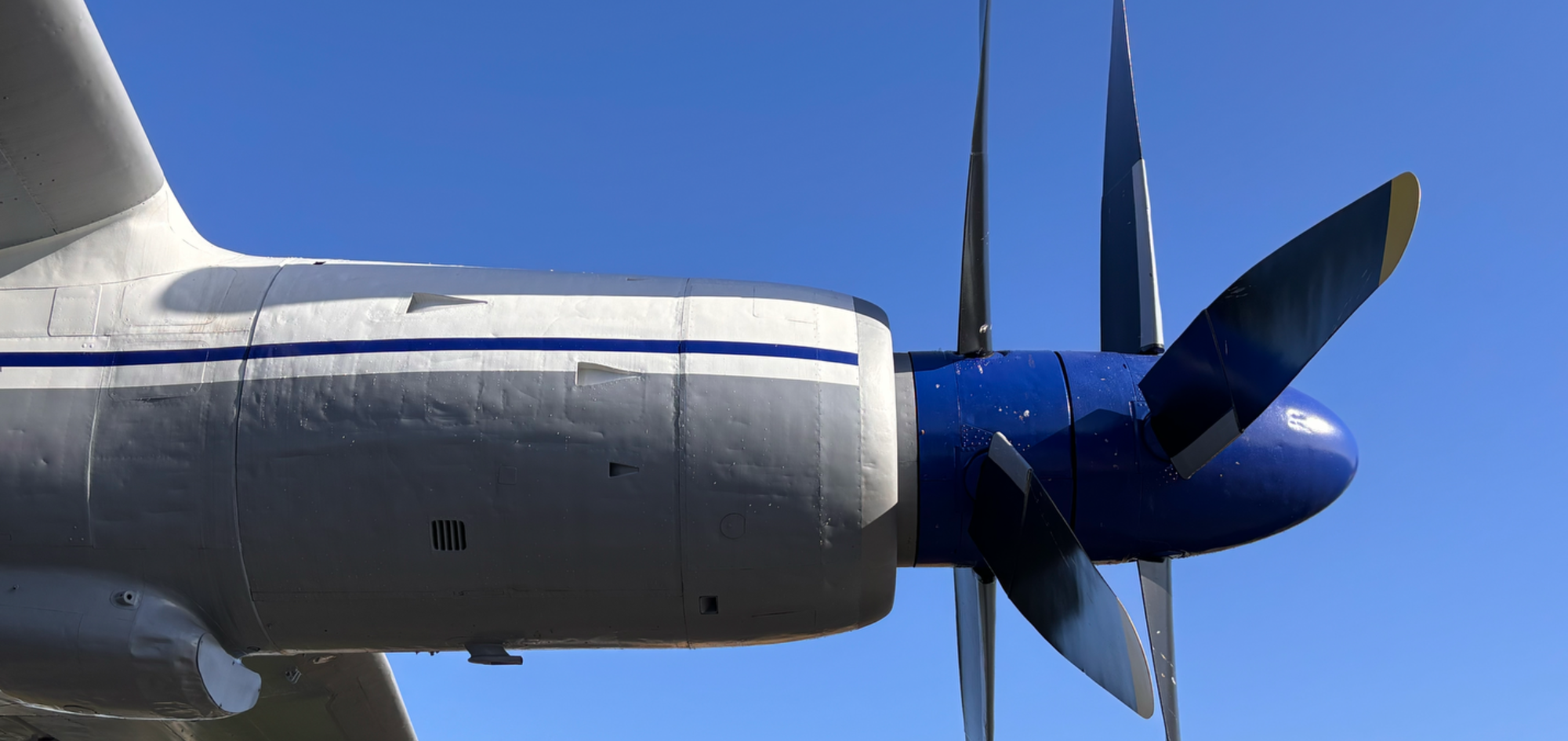 Propeller und Triebwerk eines Flugzeugs vor blauem Himmel.